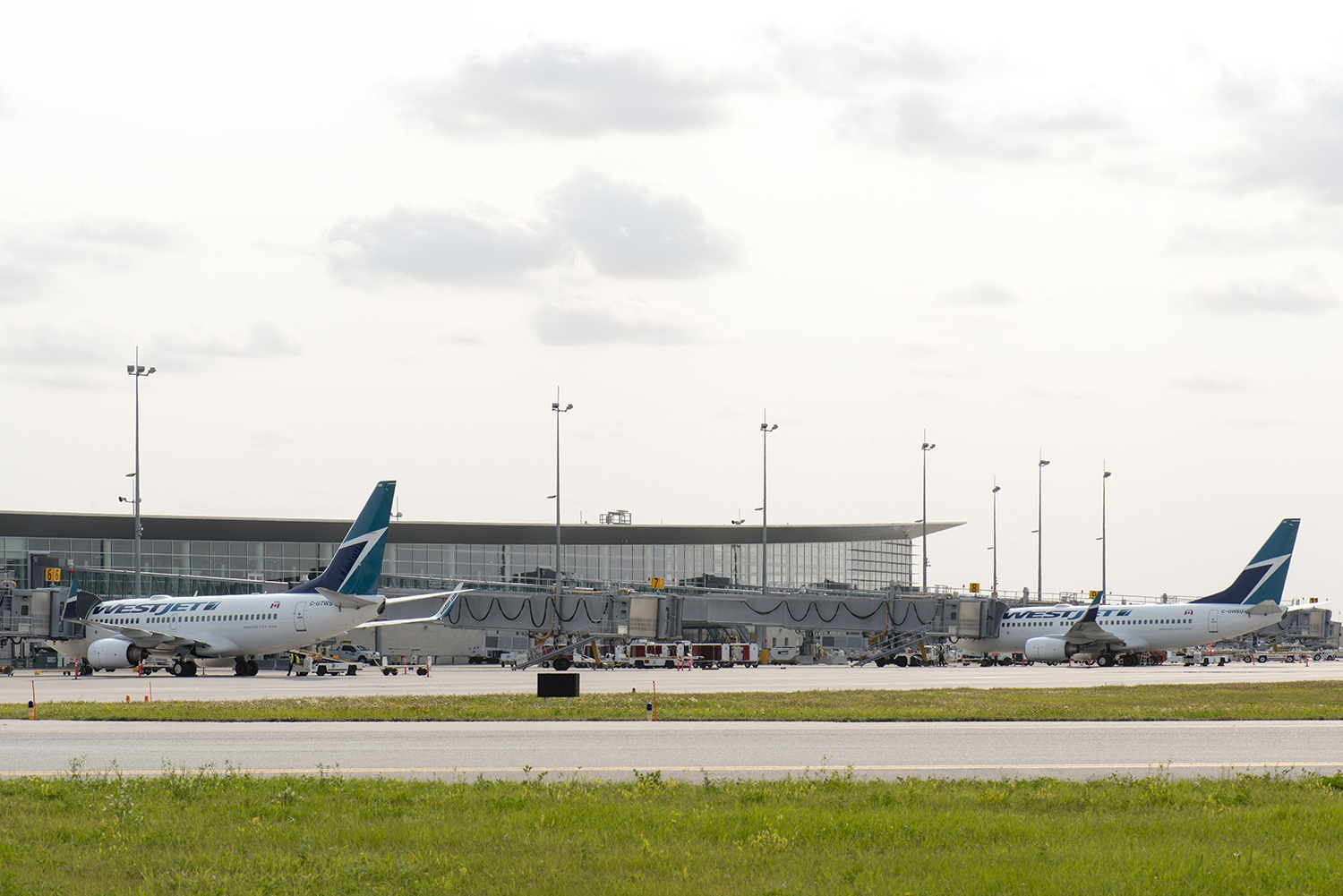 Deux avions de WestJet sont garés aux portes d'embarquement de l'aéroport international Richardson de Winnipeg.