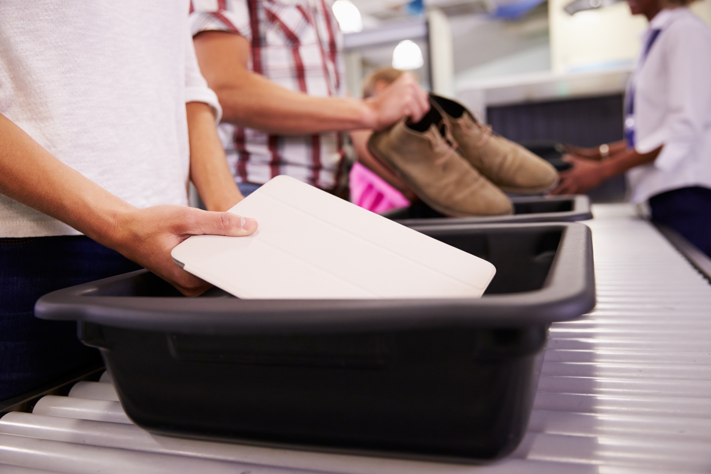 Passengers put their personal items, such as shoes and electronics, into bins.