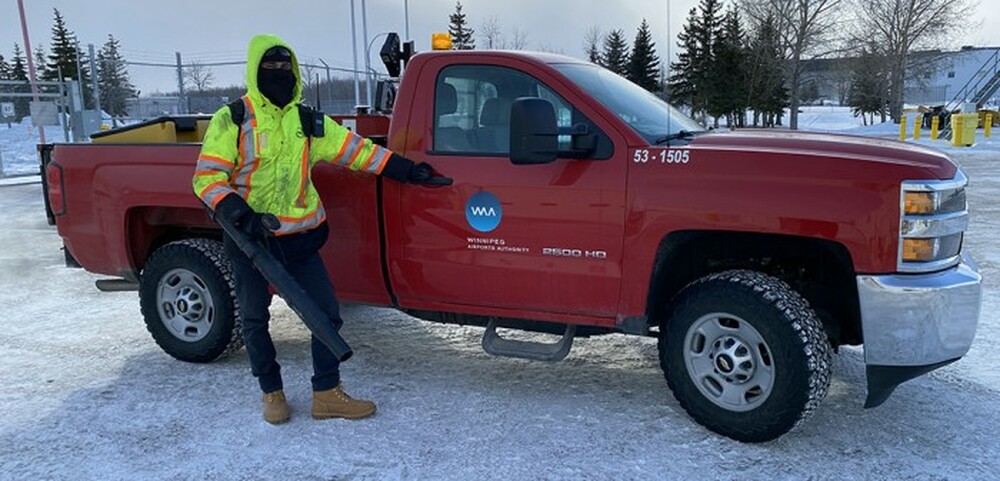 Airport employee working on the airfield in winter next to truck