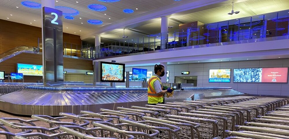 Cleaning team member sanitizing baggage carts in the Arrivals Hall