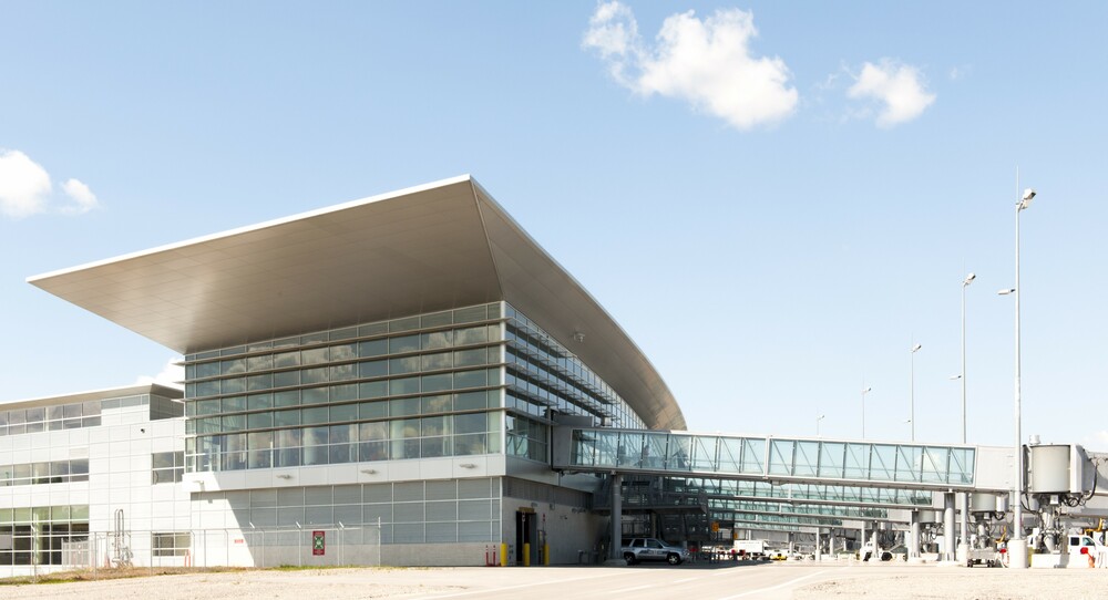 Exterior photo of the airport in the summer with five bridges in view.